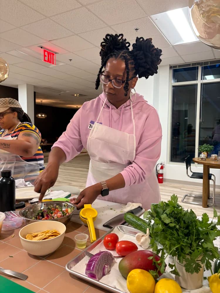 An adult student prepares fresh ingredients in the Kind Kitchen classroom